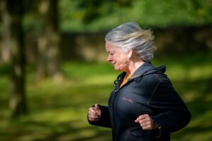 a woman running in a park with trees in the background